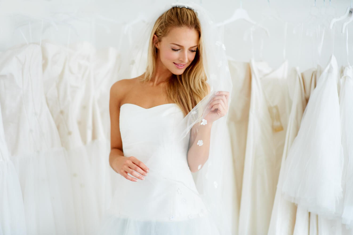 a blonde woman in a bridal store is trying on her wedding dress for the first time