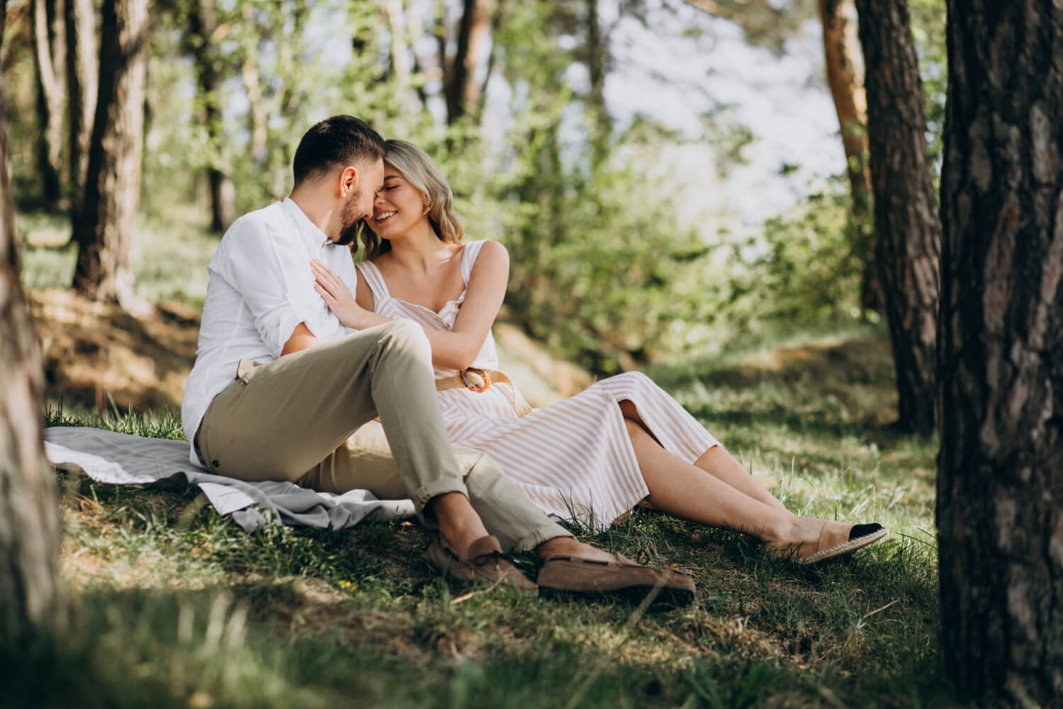 a couple sitting together on a blanket in the forest