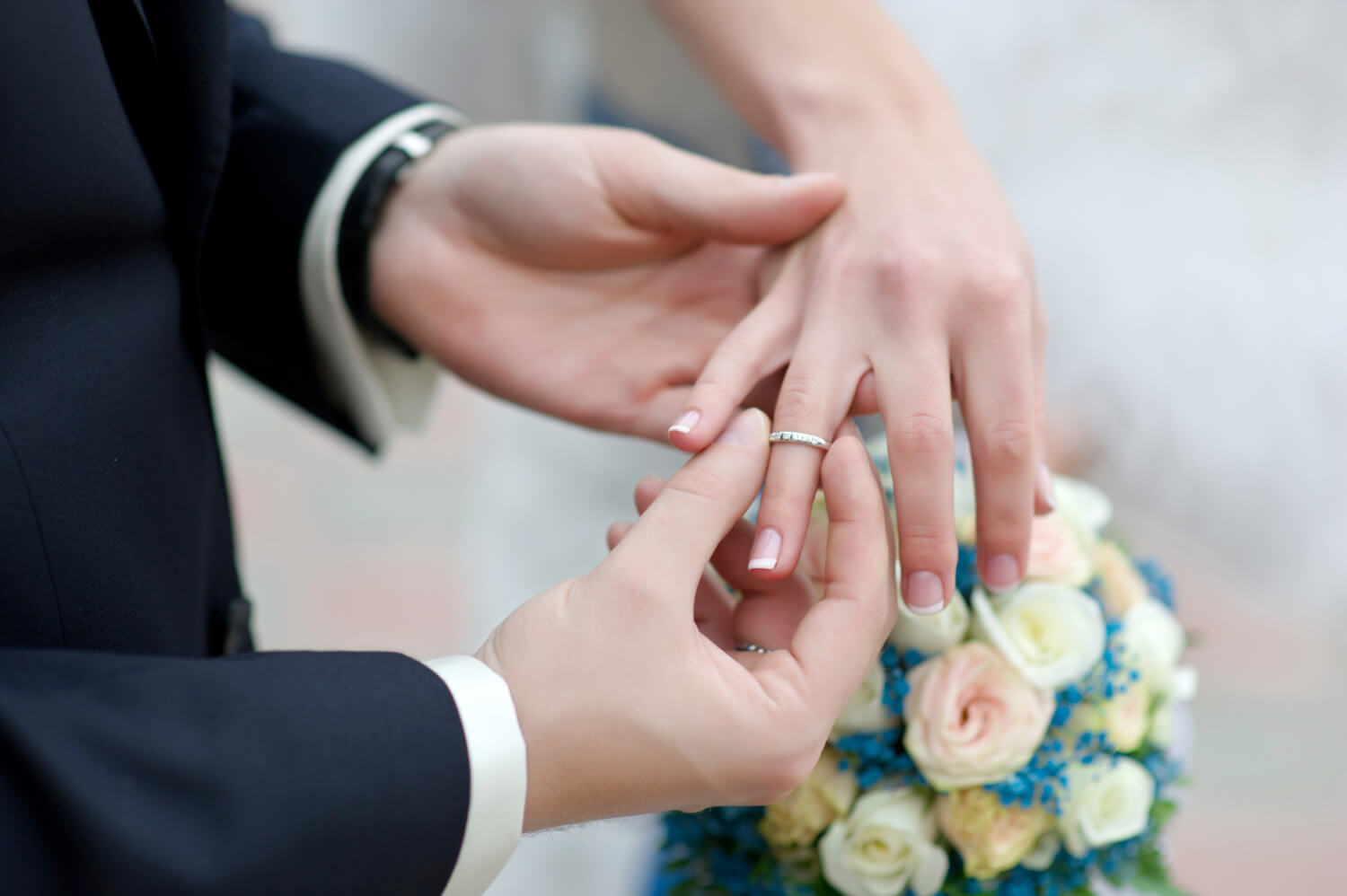 groom is putting the ring on the finger of the bride