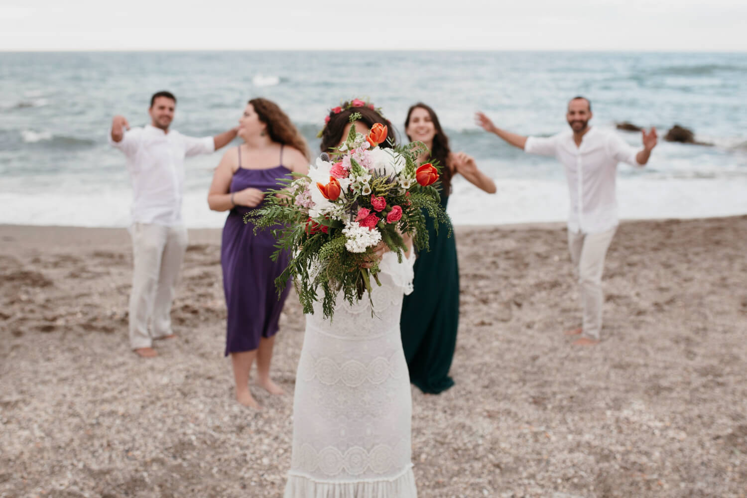 a bride is holding a flower bouquet in both hands, a group of people standing behind her