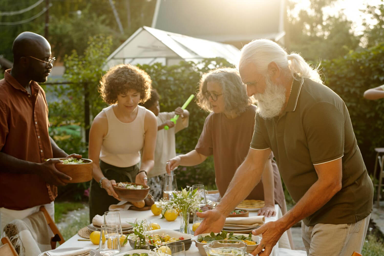 a family gathering, four people of different age bringing food to a table