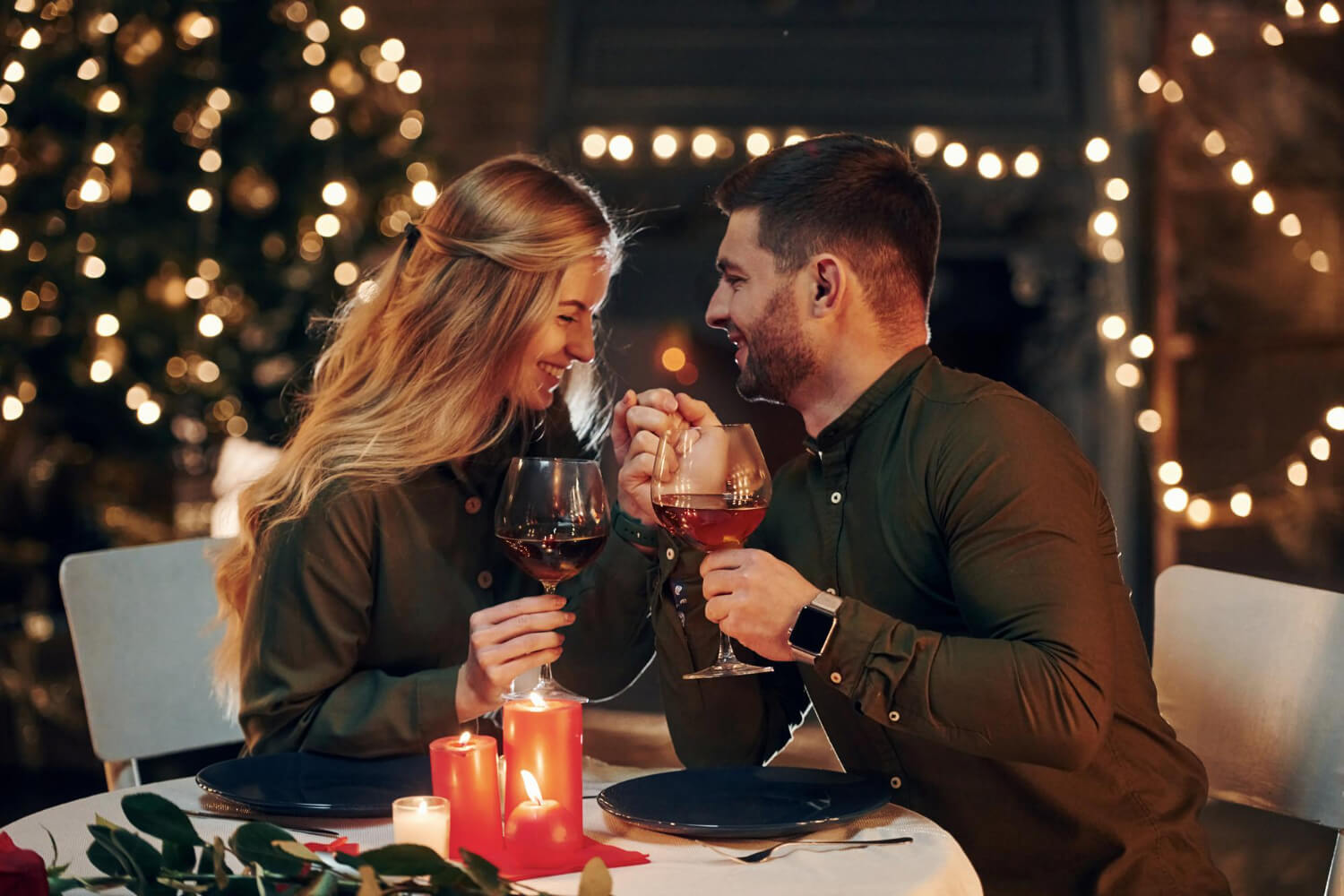 couple sitting together holding hands and drinking a glass of wine