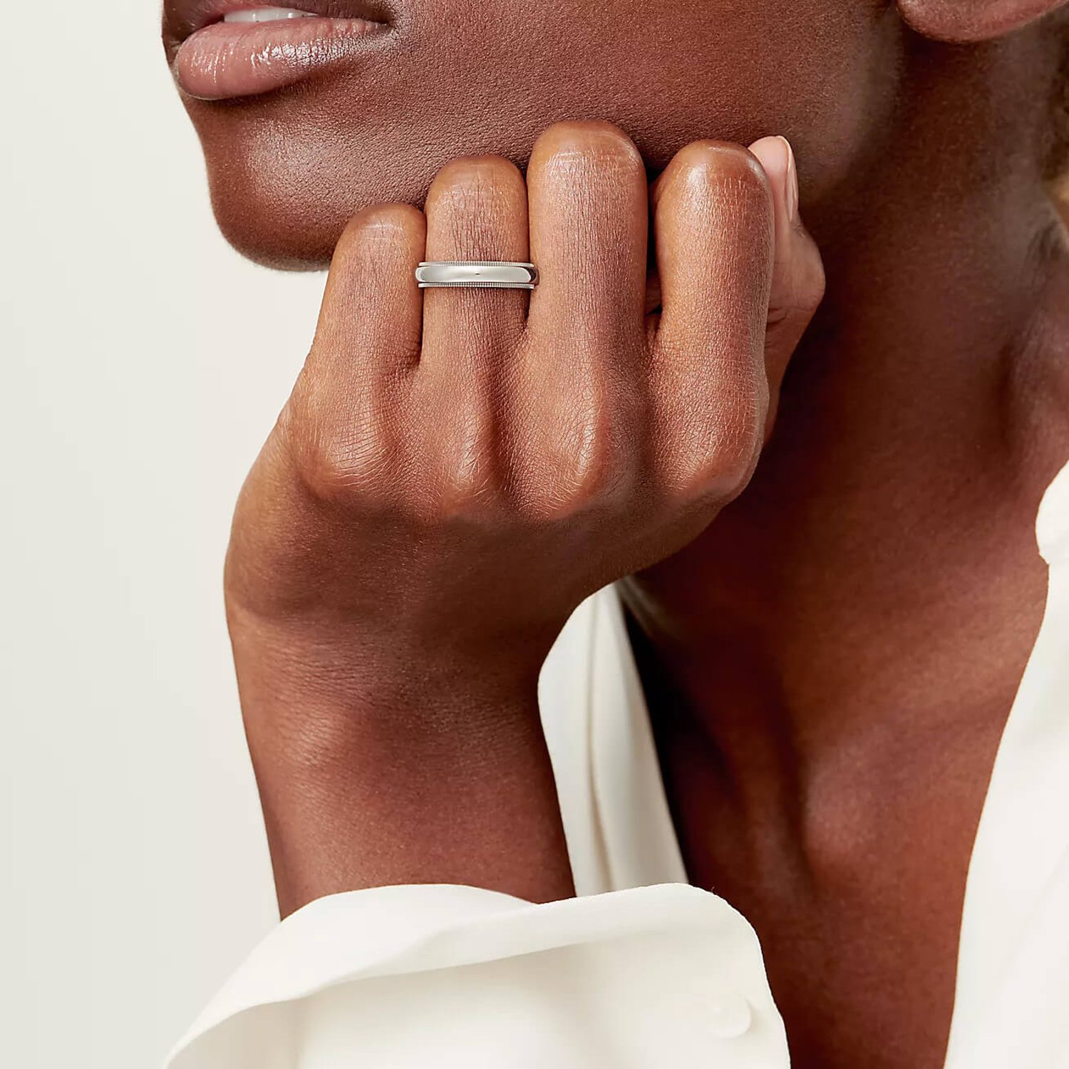 black woman is wearing a platinum wedding ring on her hand