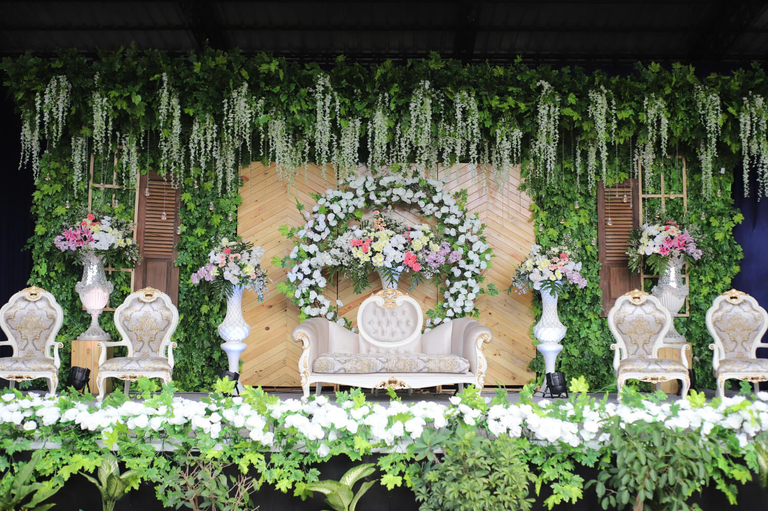 a stage decorated for a wedding with many flowers and seating chairs for the bride and groom and their family