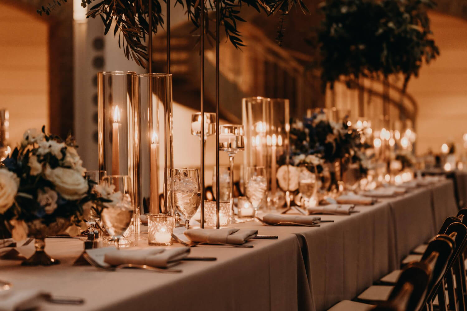 a dining table decorated with flowers and large candles in glass