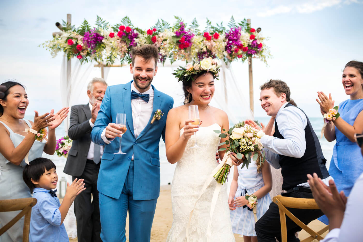 bride and groom holding a champagne glass shortly after the wedding ceremony and the guests are clapping