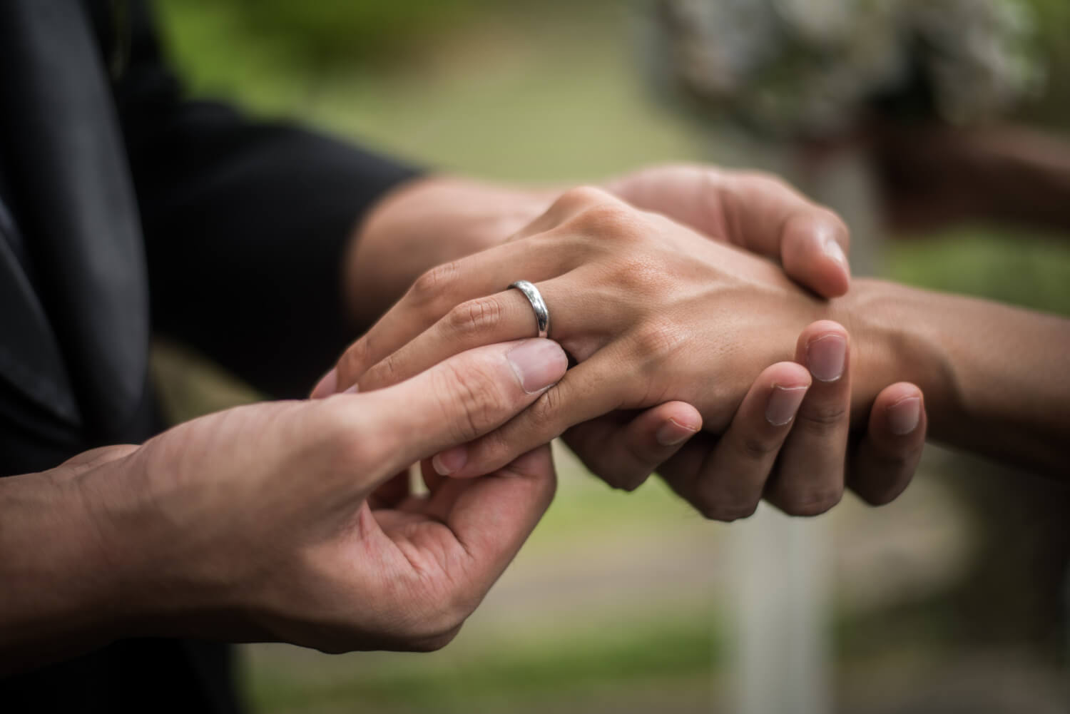 groom is putting on the ring on the bride finger