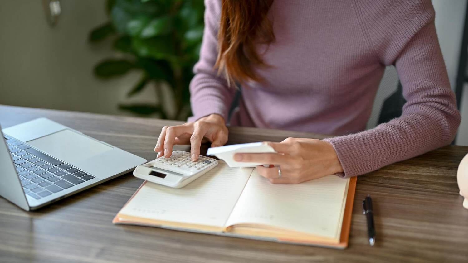 a woman sitting on a desk using a calculator and holding a note in the other hand