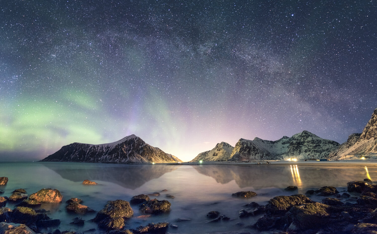 panorama of aurora borealis with milky way galaxy over snow mountain in iceland coastline