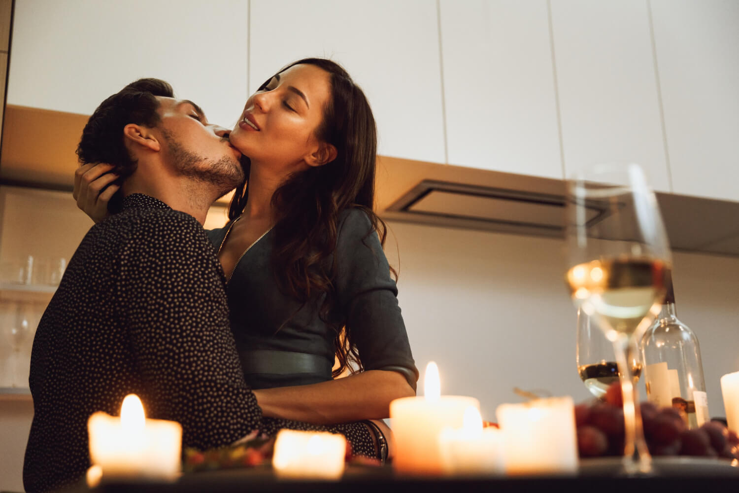 a man kissing a woman on her chin in the kitchen