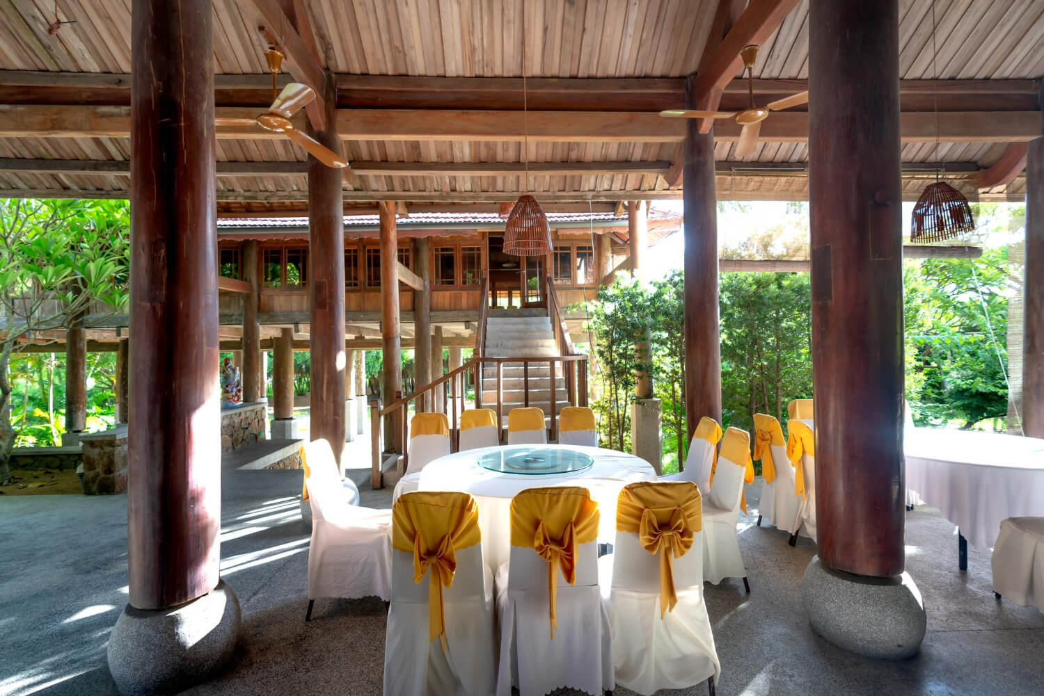 an outdoor area of an Asian-style building with wooden pillars featuring two dining tables