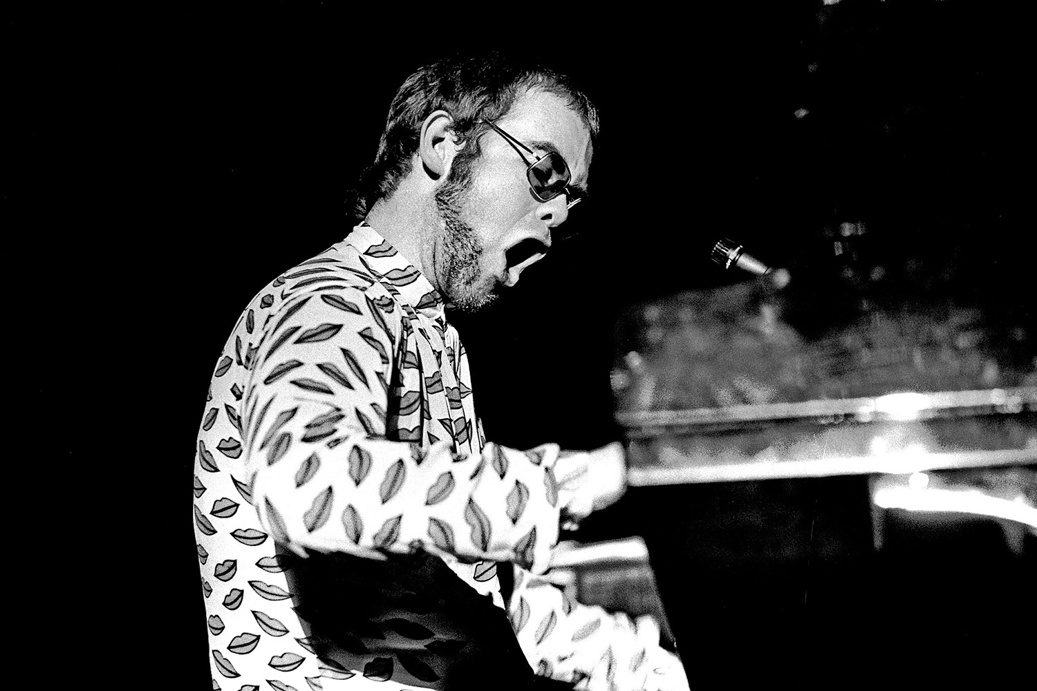 a photo taken in the 1970s of elton john sitting on a piano performing a song