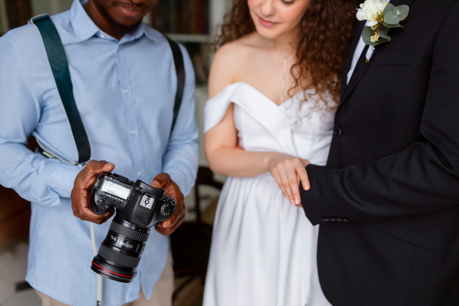 photographer is showing the photo he took with his camera to the bride and groom