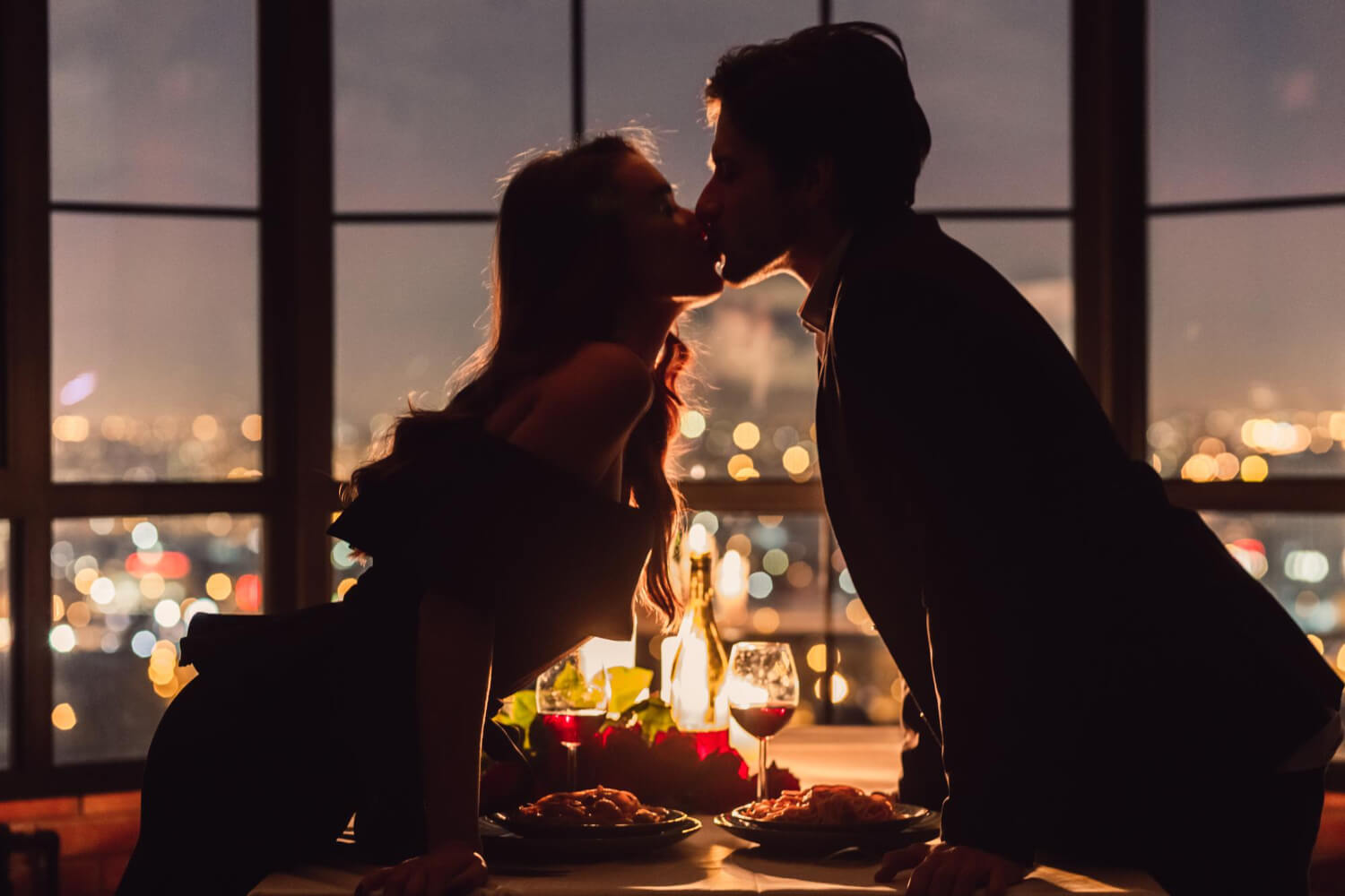 a couple having dinner and romantically kissing