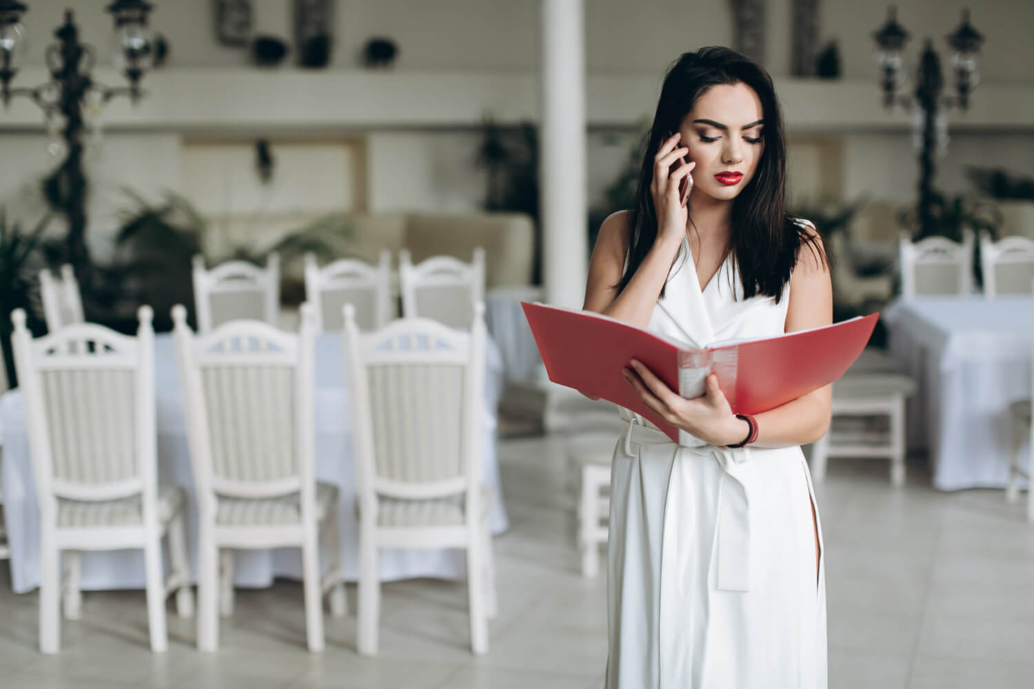 a woman is standing in a wedding venue having a phone call